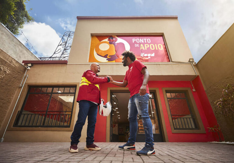 dois homens se comprimentando em frente a um estabelecimento ifood
